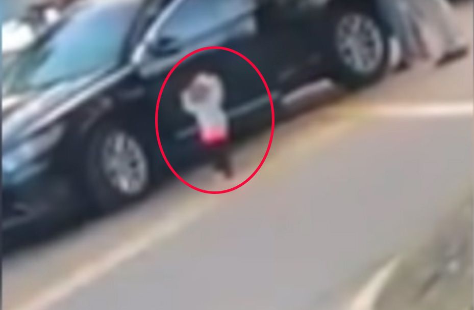 Niña de dos años con brazos en alto mientras arrestan a sus padres